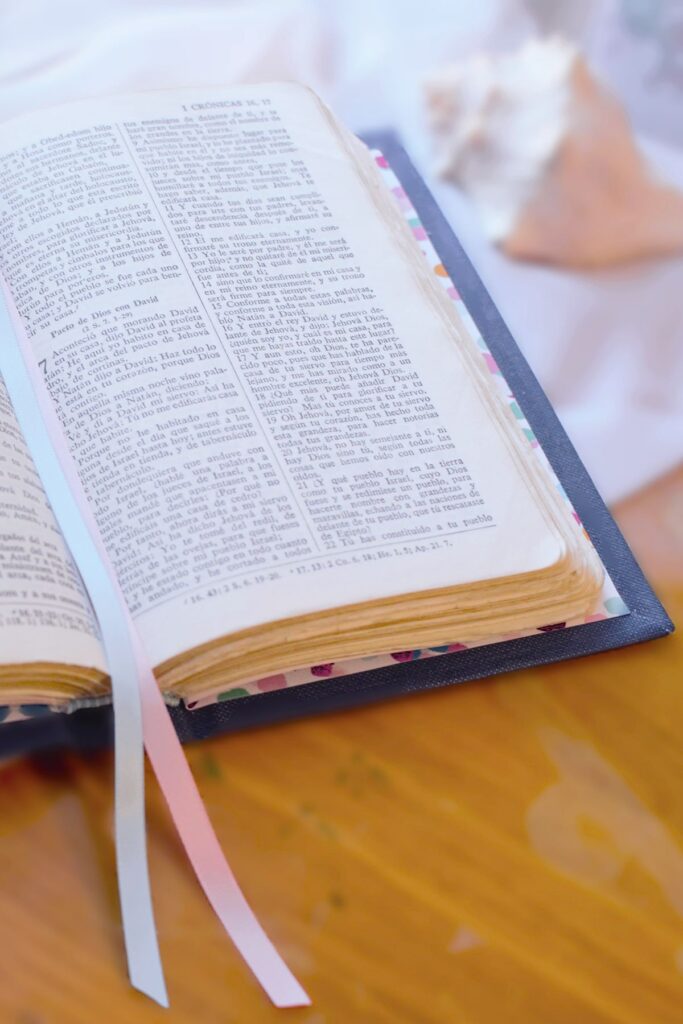 an open bible with pink and blue ribbons