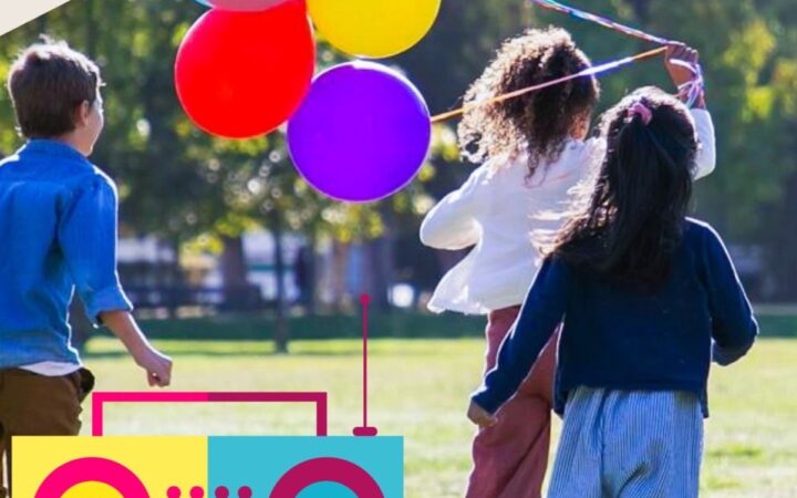 Kids running in a field with ballons and a speaker