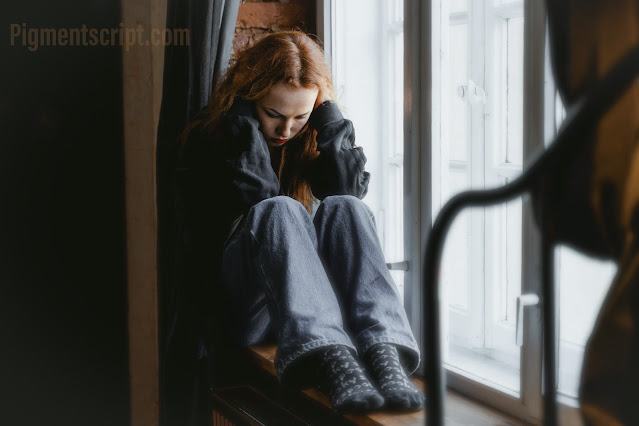 girl in blue jeans sitting on the window bench sad