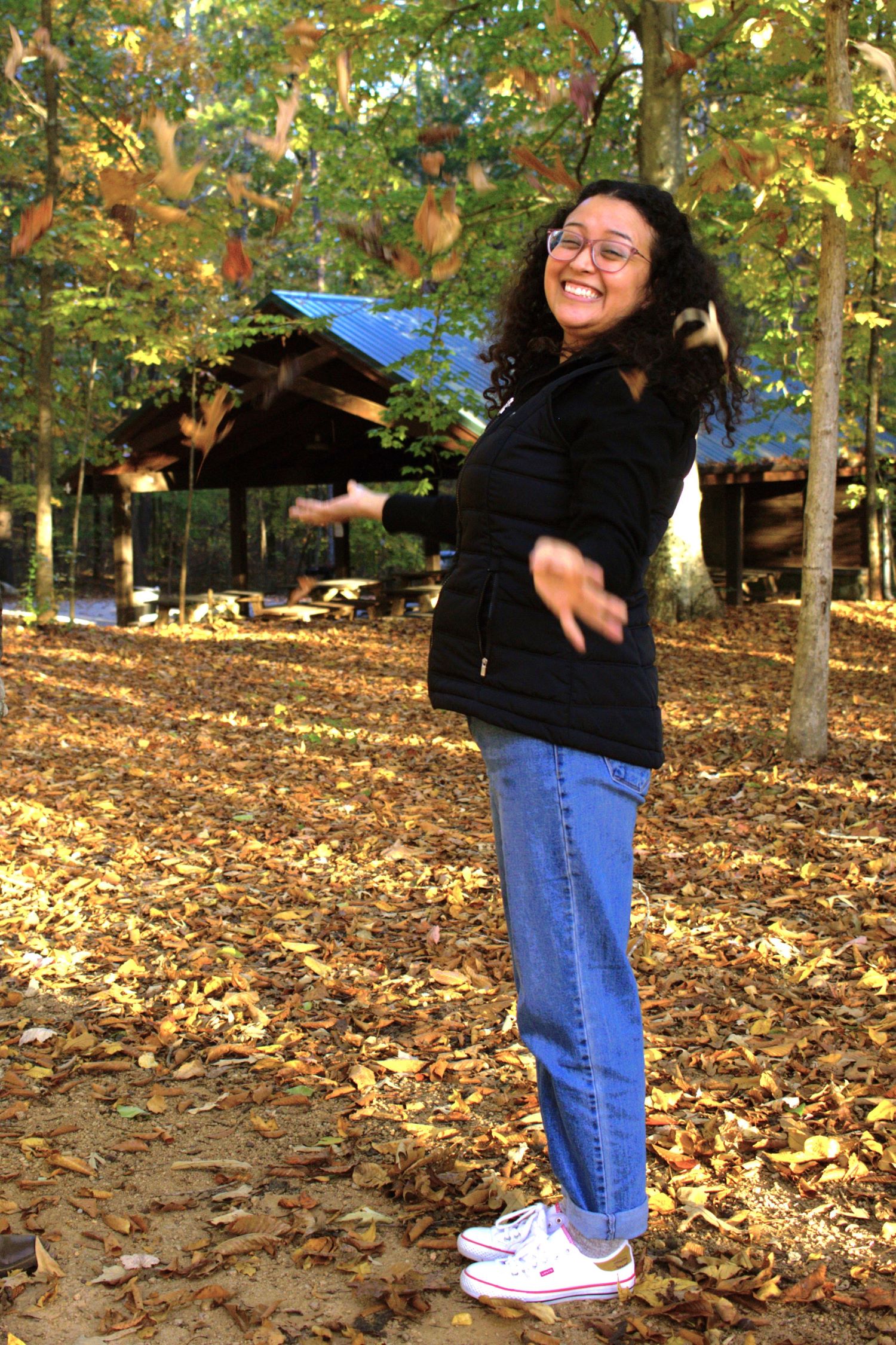 woman smiling and throwing leaves in the air