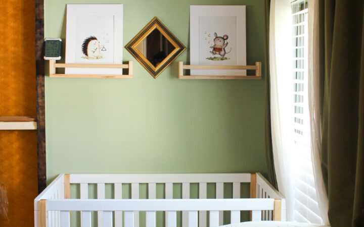 baby in white mini crib shared nursery in green
