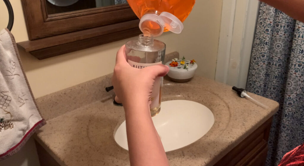 hands holding a glass soap bottle