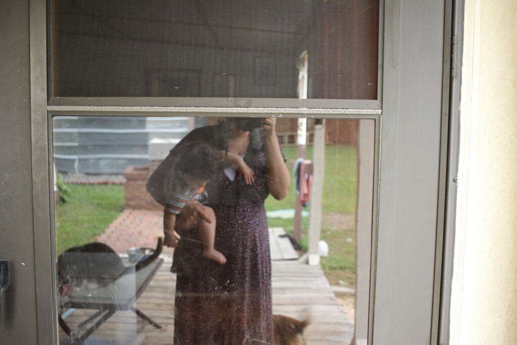 woman with baby looking at reflection in the glass of the door